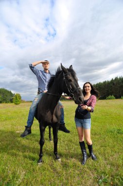 Çocuğu bekliyor, çayırda yürüyor. Ekose fanila gömlekli genç bir çift - uzun saçlı, uzun boylu, yakışıklı bir esmer, adam uzun boylu ve cesur, siyah bir ata biniyor..