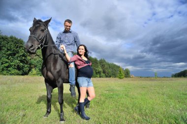 Çocuğu bekliyor, çayırda yürüyor. Genç bir çift - o uzun saçlı yakışıklı bir esmer, hamile; o uzun boylu ve cesur, siyah bir ata biniyor.