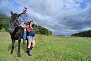 Çocuğu bekliyor, çayırda yürüyor. Genç bir çift - o uzun saçlı yakışıklı bir esmer, hamile; o uzun boylu ve cesur, siyah bir ata biniyor.