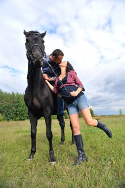 Çocuğu bekliyor, çayırda yürüyor. Ekose fanila gömlekli genç bir çift - uzun saçlı, uzun saçlı, yakışıklı bir esmer; adam uzun boylu ve cesur, siyah bir ata biniyor. Öpüşme