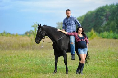 Çocuğu bekliyor, çayırda yürüyor. Genç bir çift - o uzun saçlı yakışıklı bir esmer, hamile; o uzun boylu ve cesur, siyah bir ata biniyor.