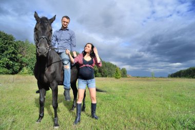 Çocuğu bekliyor, çayırda yürüyor. Genç bir çift - o uzun saçlı yakışıklı bir esmer, hamile; o uzun boylu ve cesur, siyah bir ata biniyor.