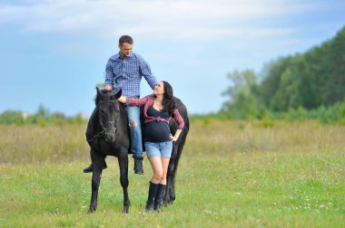 Çocuğu bekliyor, çayırda yürüyor. Genç bir çift - o uzun saçlı yakışıklı bir esmer, hamile; o uzun boylu ve cesur, siyah bir ata biniyor.