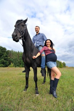 Çocuğu bekliyor, çayırda yürüyor. Genç bir çift - o uzun saçlı yakışıklı bir esmer, hamile; o uzun boylu ve cesur, siyah bir ata biniyor.