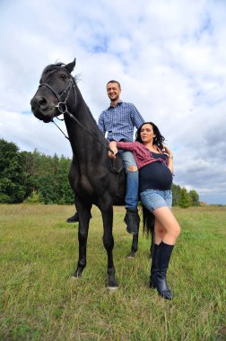 Çocuğu bekliyor, çayırda yürüyor. Ekose fanila gömlekli genç bir çift - uzun saçlı, uzun boylu, yakışıklı bir esmer, adam uzun boylu ve cesur, siyah bir ata biniyor..