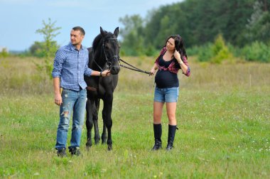 Çocuğunu bekliyor. Çayırda yürüyorum. Genç bir çift - o uzun saçlı esmer bir kadın, hamile; uzun boylu ve cesur, siyah atın dizginlerini tutan, çayırda bir yürüyüş.