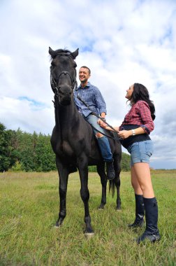 Çocuğu bekliyor, çayırda yürüyor. Genç bir çift - o uzun saçlı yakışıklı bir esmer, hamile; o uzun boylu ve cesur, siyah bir ata biniyor.