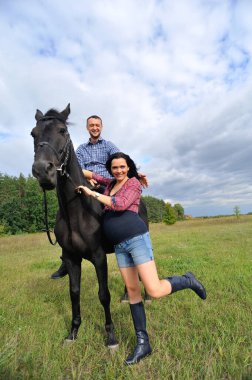 Çocuğu bekliyor, çayırda yürüyor. Genç bir çift - o uzun saçlı yakışıklı bir esmer, hamile; o uzun boylu ve cesur, siyah bir ata biniyor.