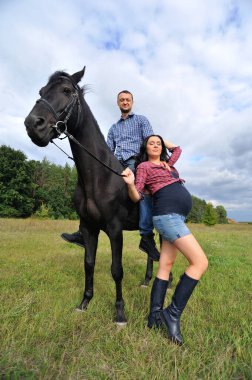 Çocuğu bekliyor, çayırda yürüyor. Genç bir çift - o uzun saçlı yakışıklı bir esmer, hamile; o uzun boylu ve cesur, siyah bir ata biniyor.