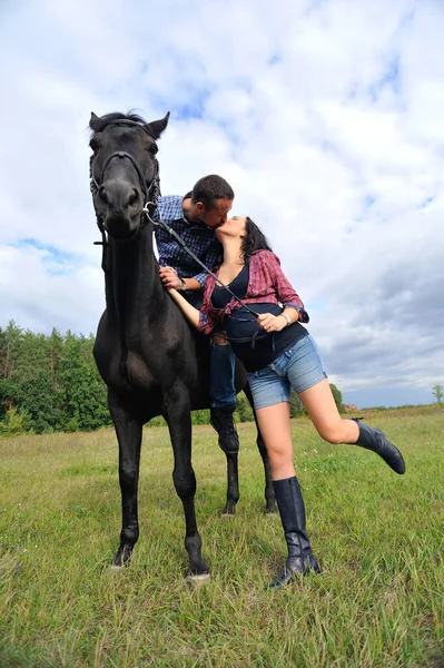 Çocuğu bekliyor, çayırda yürüyor. Ekose fanila gömlekli genç bir çift - uzun saçlı, uzun saçlı, yakışıklı bir esmer; adam uzun boylu ve cesur, siyah bir ata biniyor. Öpüşme