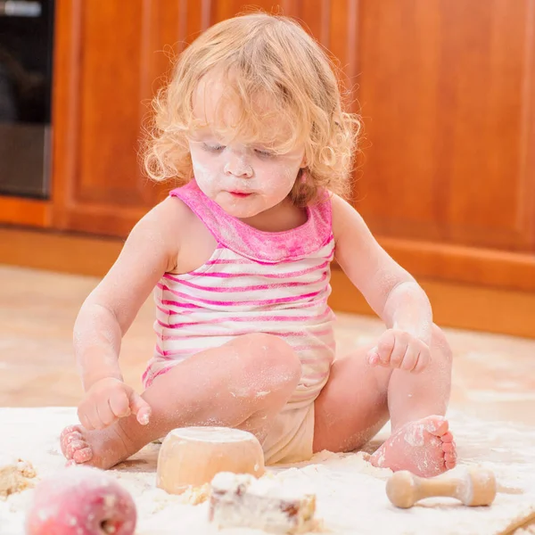 Κορίτσι Κάθεται Στο Πάτωμα Της Κουζίνας Λερωμένο Αλεύρι Παίζοντας Φαγητό — Φωτογραφία Αρχείου