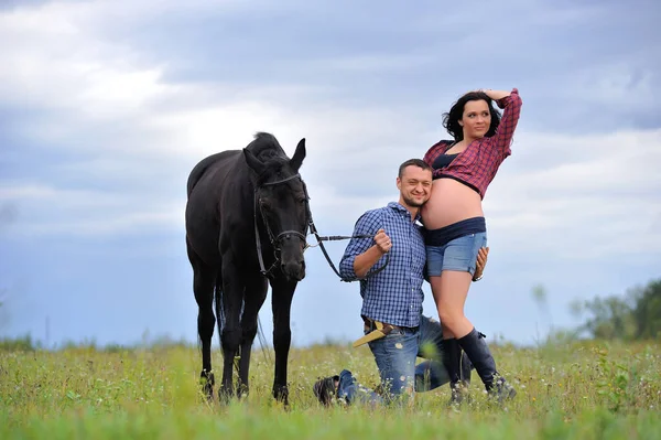 Mutlu çift - uzun saçlı, uzun saçlı, yakışıklı esmer; adam dizlerinin üzerinde, onun göbeğini öpüyor ve siyah atın dizginlerini tutuyor. Meadow, arkasında harika bir gökyüzü