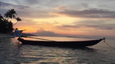 Denizin üzerinde güzel bir gün batımı ve doğa arka planında bir tekne.