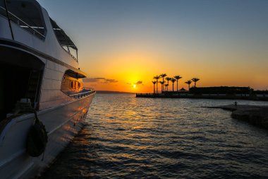 Bir yatın fotoğrafı, gündoğumunda denizde palmiyeler..