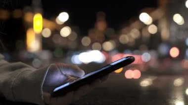 Telefonu şehrin arka planında kaydırıyorum, bokeh.