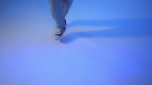 Dancer in black sneakers close up, moves on blue background studio handheld shot — Stock Video