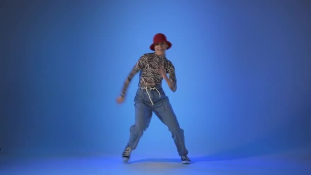 Mujer joven bailando casa, saltos de energía sobre fondo azul, toma de estudio — Vídeos de Stock