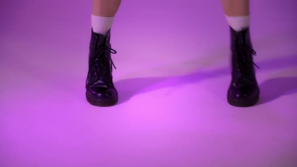 身着黑色靴子的舞蹈演员在紫罗兰的背景上跳得很近，演播室的金宝被射中了 — 图库视频影像