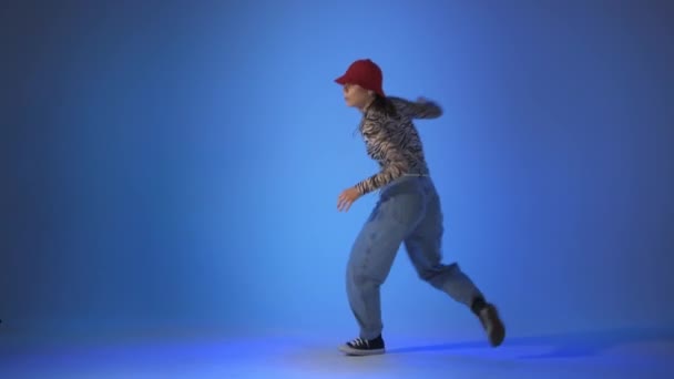 Mujer joven bailando casa, saltos de energía sobre fondo azul, toma de estudio — Vídeos de Stock