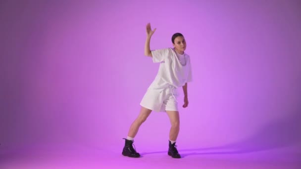 Jeune femme dansant hip hop sur fond violet, plan studio — Video