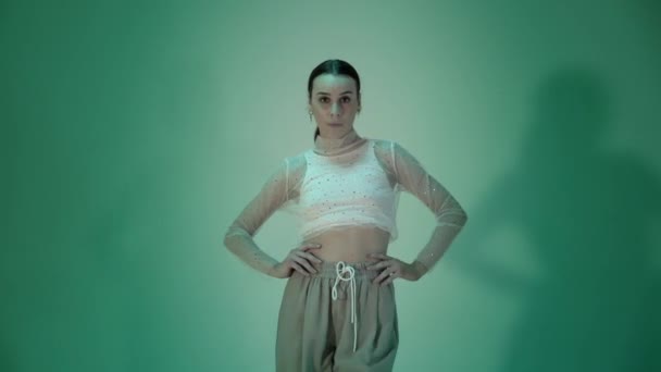 Chica bailando vogue en ropa deportiva blanca sobre fondo verde, toma de estudio — Vídeo de stock