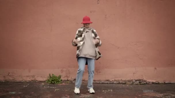 Молода жінка хіп-хоп вуличний танець на тлі коричневої стіни, постріл — стокове відео