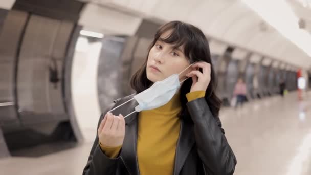 Jovem mulher colocar máscara protetora dentro da estação de metro perto da plataforma — Vídeo de Stock