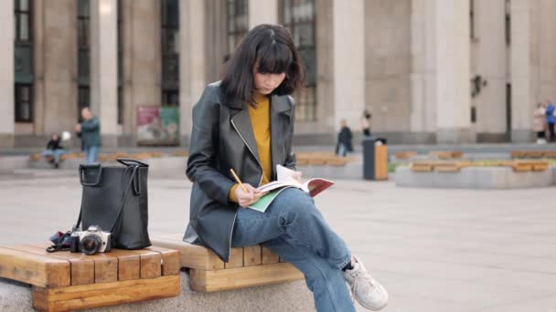 Жінка студент перевертається через книгу на лавці біля університету — стокове відео