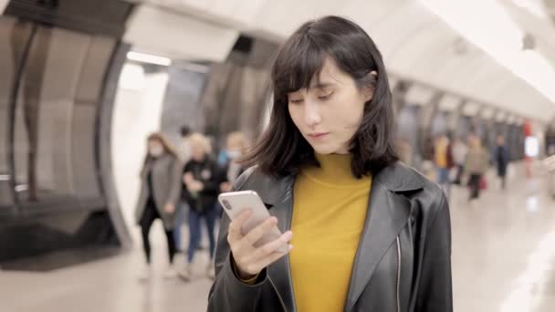 Ung asiatisk kvinna med telefon inne tunnelbanestation, med hjälp av telefon under jord — Stockvideo