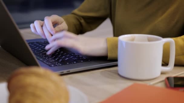 Tangan wanita mengetik di laptop di dalam ruangan, menutup tempat kerja dan minum kopi — Stok Video