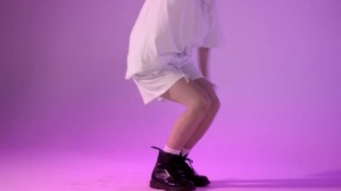 Mor arka planda siyah çizmeli hip-hop dansçısı, yüz çekimi yok.