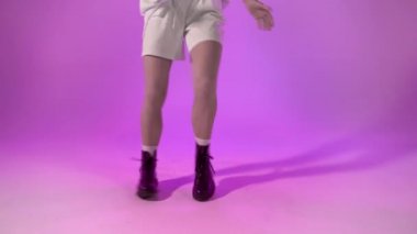 Mor arka planda siyah çizmeli hip-hop dansçısı, yüz çekimi yok.