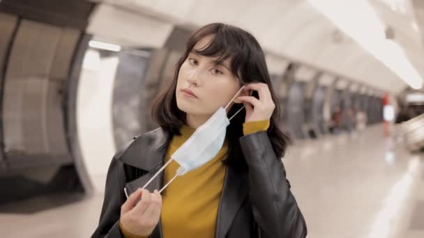 Jovem mulher colocar máscara protetora dentro da estação de metro e andar — Vídeo de Stock