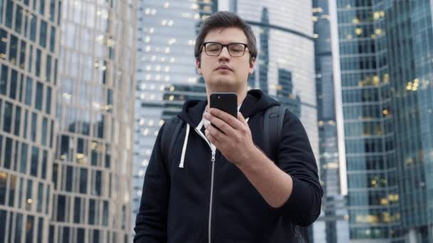 Man standing with a phone on background of business centre skyscrapers — Stock Video