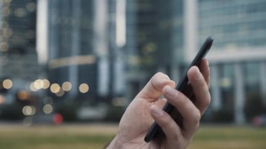 Bulanık iş binalarının arka planında telefonları kaydıran eller