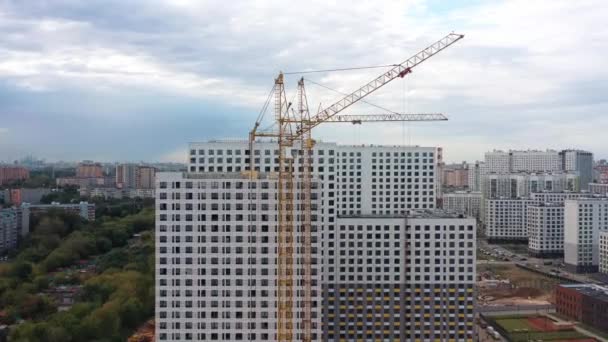Building cranes, residential apartment houses under construction, drone zoom in — Stock Video