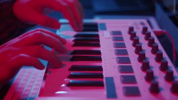 Handen met behulp van midi toetsenbord in huis studio in de nacht met neon lichten — Stockvideo