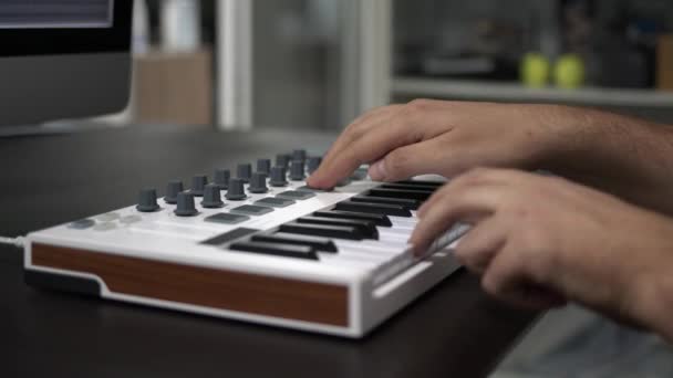 Manliga händer spelar midi tangentbord med kuddar på bordet i hemstudio — Stockvideo