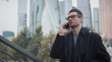 Paltolu bir adam telefonda konuşuyor sonbahar günü gökdelenlerin arka planında