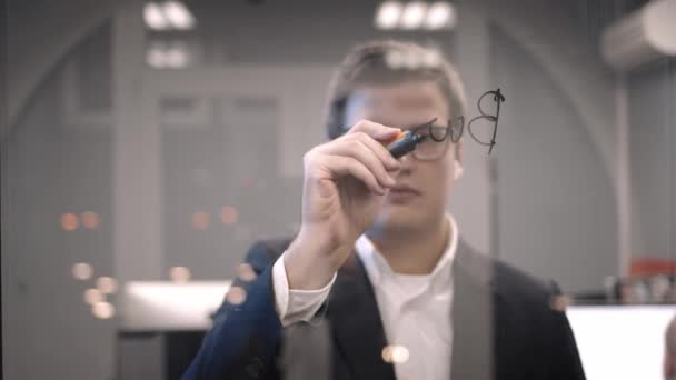 Young boss businessman writing business plan on the glass wall in the office — Stock Video