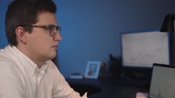 Человек трейдер смотрит на экран с графиками фондового рынка, домашний офис — стоковое видео