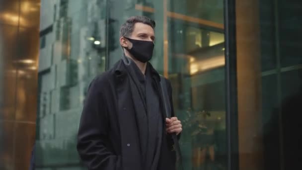 身穿黑衣、戴着防护面具的男子沿街行走 — 图库视频影像