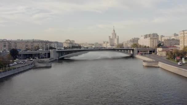 Drone tiro zoom de paisaje urbano con río y puente, coches y árboles — Vídeo de stock