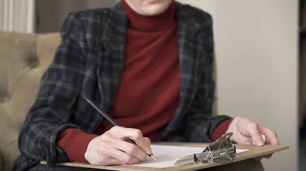 Female manager hands in chair, making notes in paper holding a pencil
