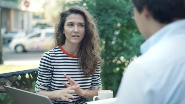 Mujer joven y hombre informal discutiendo negocios en la cafetería de la ciudad al aire libre — Foto de Stock