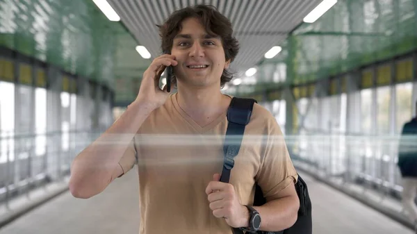 Giovane uomo allegro con il telefono in mano, in aeroporto al chiuso — Foto Stock