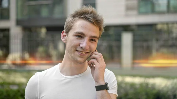 Giovane uomo biondo che parla al telefono fuori in estate, bagliore delle lenti — Foto Stock