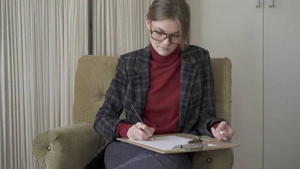 Sandalyedeki gözlüklü kadın yönetici, kağıda not alıyor. — Stok fotoğraf