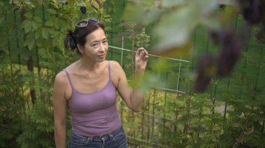 Bahçede yeşil bitkilerle duran Asyalı kadın, en iyi görüntü.