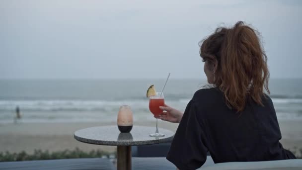 Портативный снимок женщины, сидящей спиной и смотрящей на волны — стоковое видео